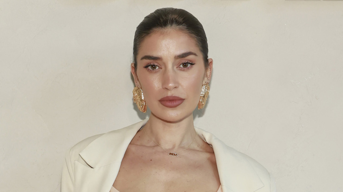Nicole Williams English poses in a cream-colored corset top, a matching blazer and oversized gold earrings.